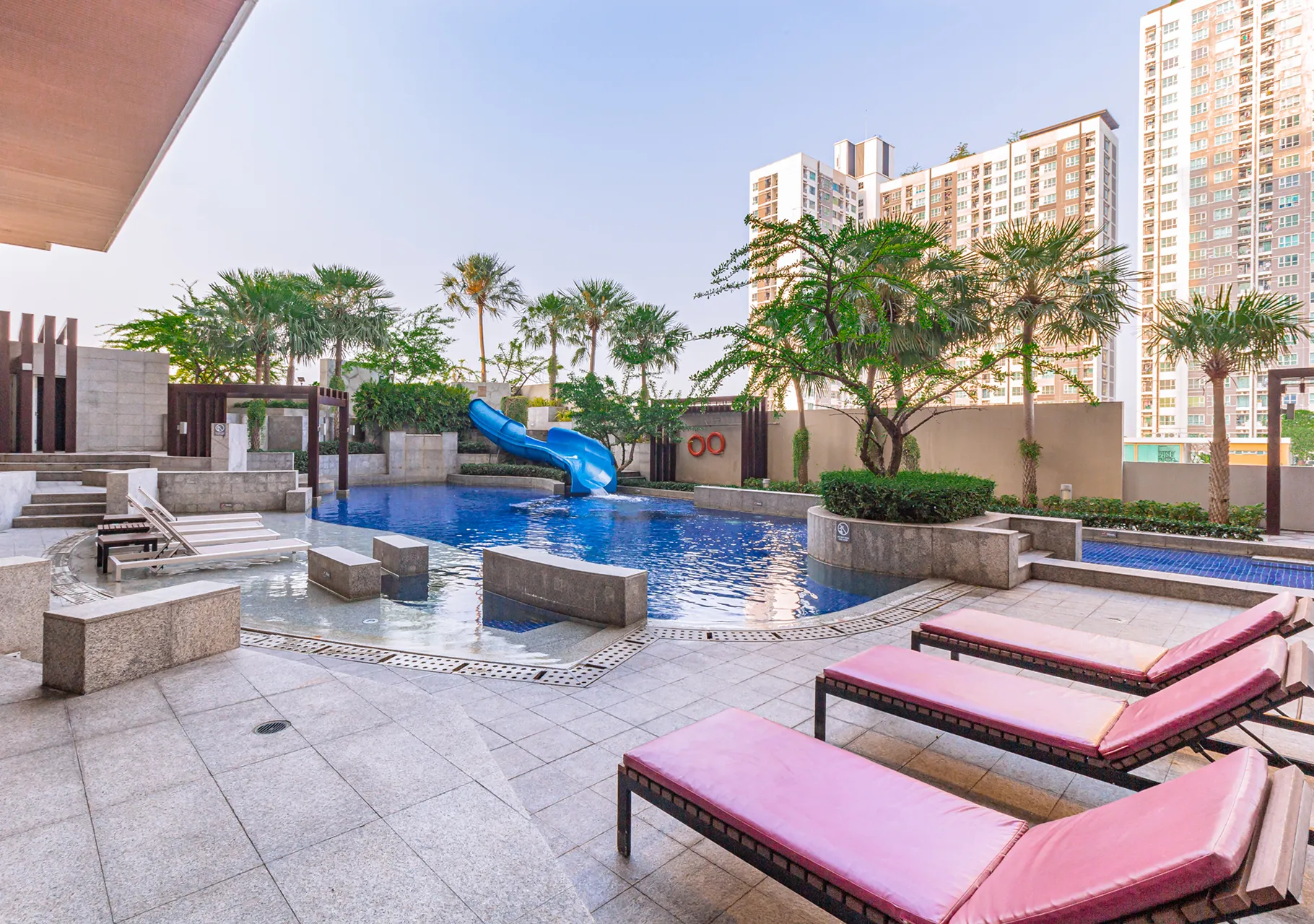 Poolside loungers beside the swimming pool at a Bangkok hotel with leisure area.